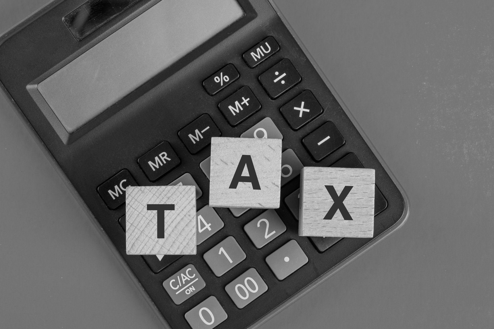 Letter tiles spelling TAX on a calculator